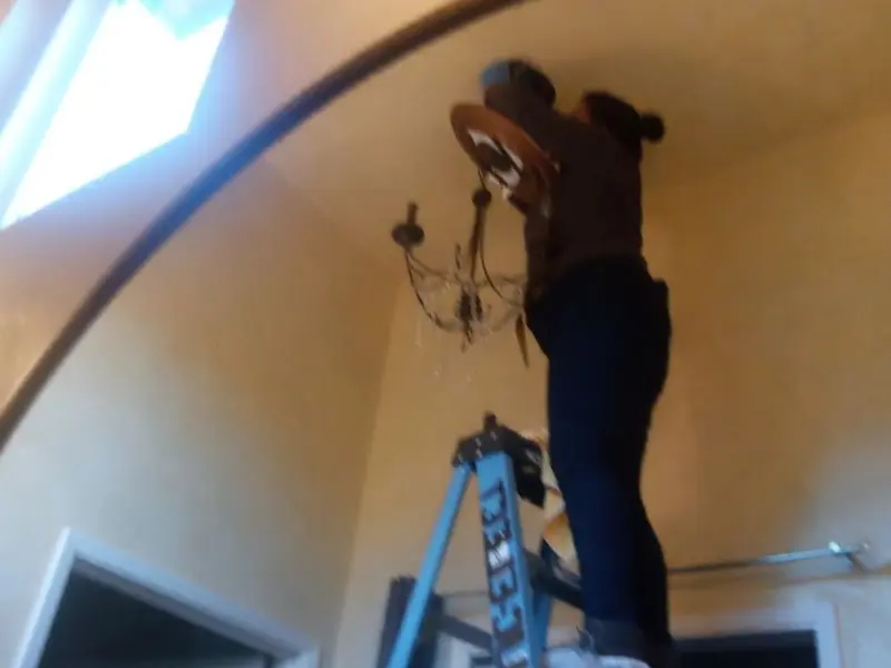 Electrician installing a chandelier in a Monitor residence